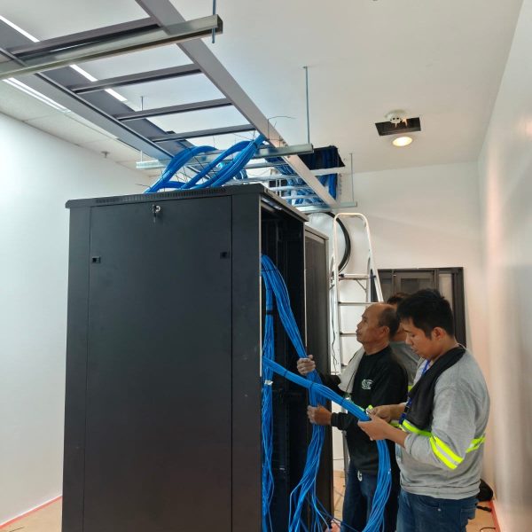IT technicians routing blue structured cabling into a data center server rack
