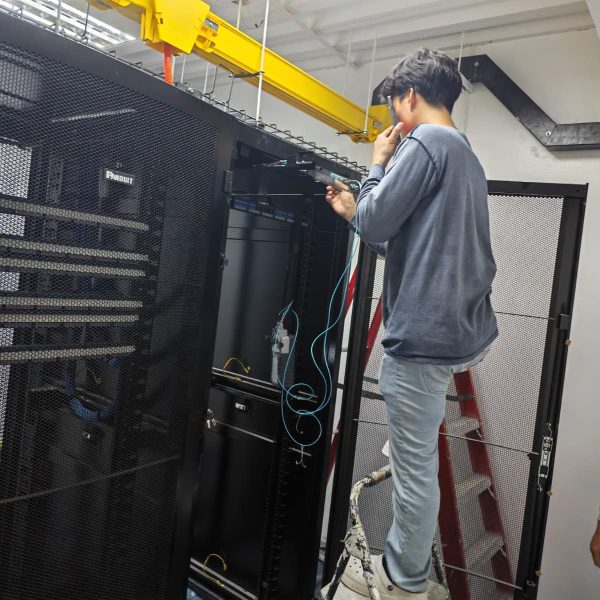 IT engineer on a ladder configuring structured cabling in a data center