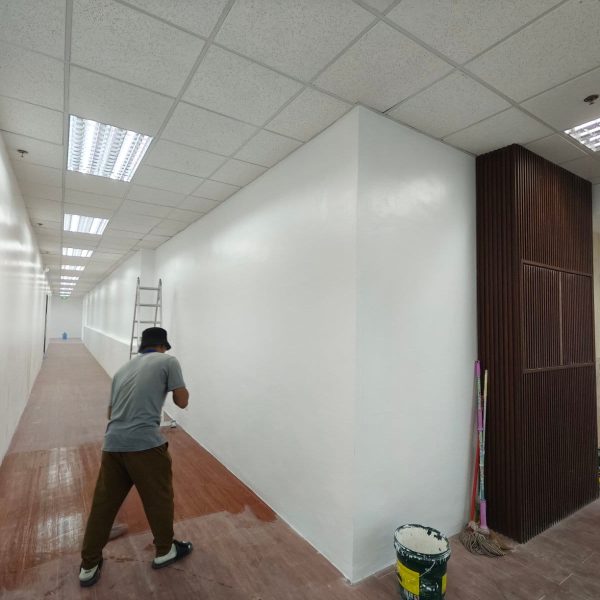 Commercial fit-out construction worker painting hallway walls for a new office interior